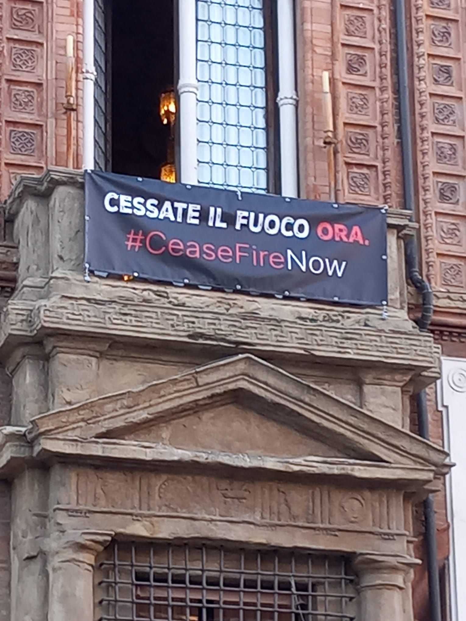 CESSATE IL FUOCO ORA. Esposto lo striscione a Palazzo d’Accursio.